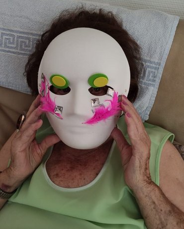 Seniorin mit weißer Maske mit Glitzersteinen