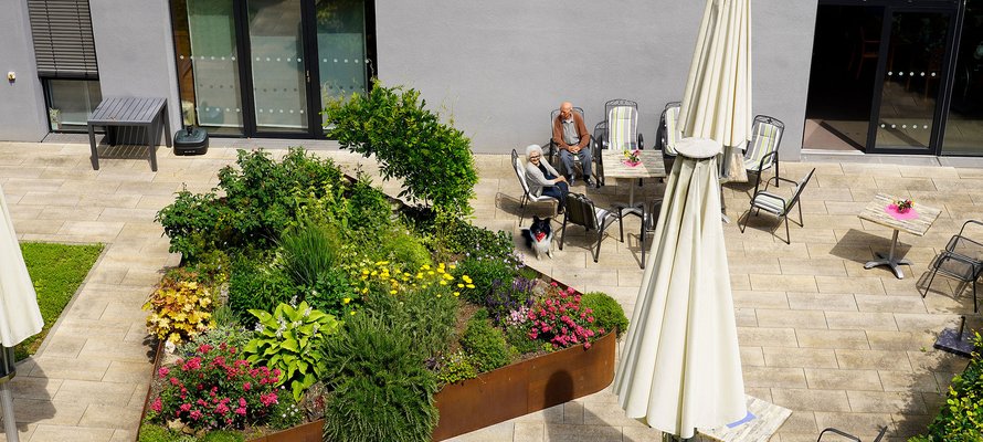 Geometrisch angelegtes Blumenbeet auf einer Terrasse mit Sitzgruppe