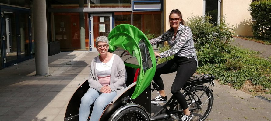 Mitarbeiterin und Seniorin bei Fahrt mit der Rikscha