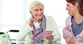 junge Frau spielt mit Seniorin Karten