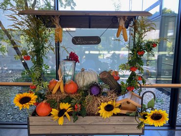 Planwagen mit Holzdach und Herbstdeko aus Sonnenblumen, Stroh und Kürbissen