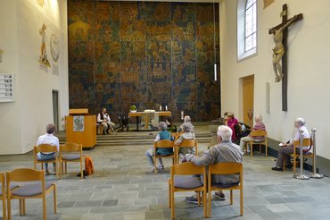 Senioren sitzen im Kirchenraum auf Stühlen und lauschen