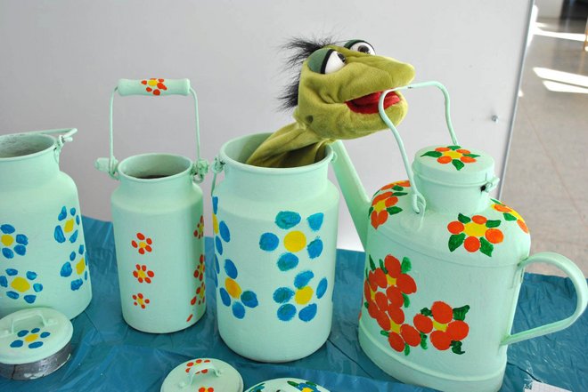 4 Milchkannen, die hellgrün und mit Blumen bemalt sind