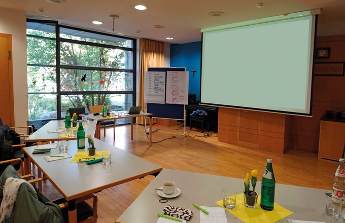 Raum für Seminare oder Veranstaltungen mit Tischen und Leinwand